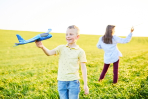 Children play in the field and imagine themselves to be pilots on a sunny summer day