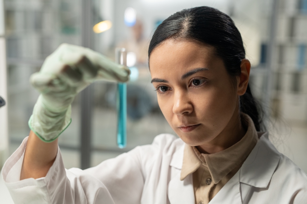 Contemporary scientist looking at flask with blue liquid substance