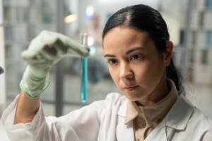 Contemporary scientist looking at flask with blue liquid substance
