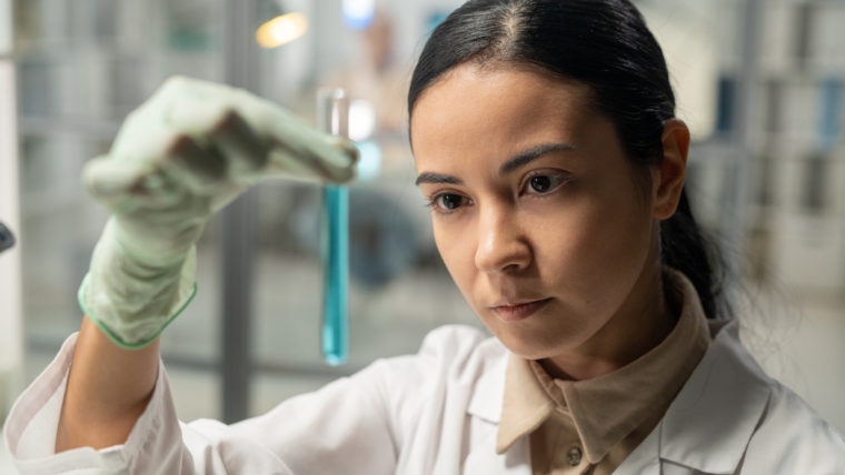 Contemporary scientist looking at flask with blue liquid substance