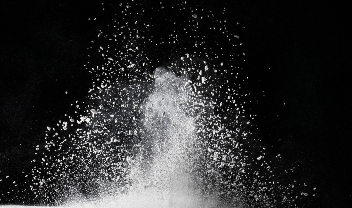 White dust exploding on surface impact