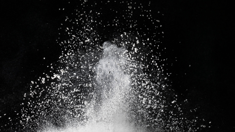 White dust exploding on surface impact